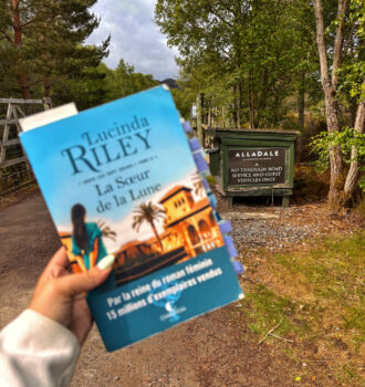 Main tenant La soeur de la lune devant le panneau d'entrée du parc d'Alladale
