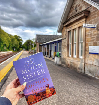 Main tenant The Moon Sister, la version originale de La soeur de la lune de Lucinda Riley devant la gare de Tain
