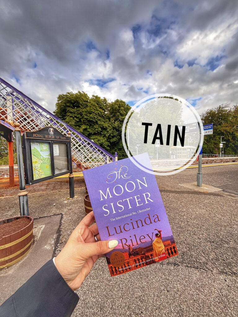 Main tenant The Moon Sister, la version originale de La soeur de la lune de Lucinda Riley devant la gare de Tain