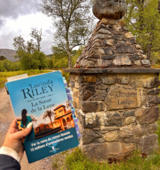 Main tenant la soeur de la lune devant le poteau de la grille du domaine avec Alladale Lodge inscrit dessus