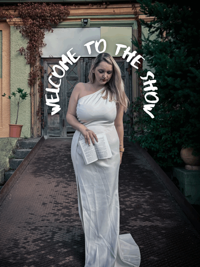Photo en robe blanche avec un livre ouvert devant une bâtisse ancienne, texte “Welcome to the show” – Le bal du cygne noir Halloween 2025.