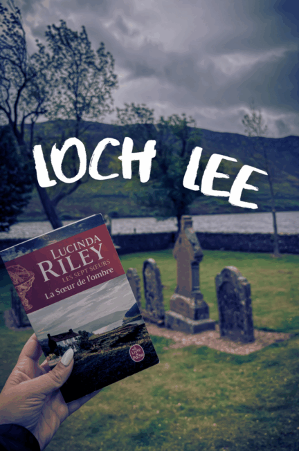 Main tenant La sœur de l’ombre de Lucinda Riley devant un petit cimetière sur les rives du Loch Lee, au cœur des Highlands écossais.