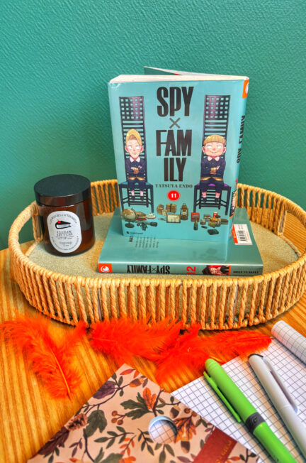 Couverture du manga Spy x Family tome 11 de Tatsuya Endo, missions 67 à 75, posée dans un panier avec des cahiers, stylos et plumes oranges, ambiance scolaire et automnale.