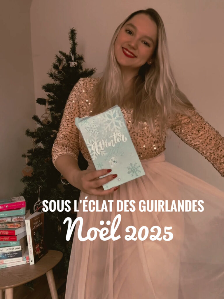 Portrait d’une femme debout devant un sapin de Noël décoré, tenant un paquet cadeau bleu pâle orné de flocons. Elle porte un haut à sequins dorés et une jupe longue rose pâle. À gauche, une petite table en bois est recouverte de piles de livres de Noël.
