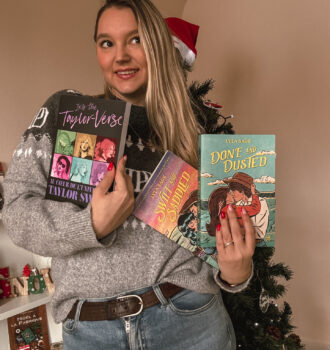 Sorbet-Kiwi tient trois ouvrages inspirés de Taylor Swift. On voit notamment Into the Taylor-Verse et deux romans aux couvertures colorées. Le sapin décoré apparaît à l’arrière-plan. - Cadeaux pour Swifties