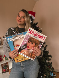 Sorbet-Kiwi tient deux magazines consacrés à Taylor Swift, dont un numéro de Rolling Stone. Un sapin décoré se trouve derrière elle. - Cadeaux pour Swifties
