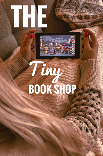 Sorbet-Kiwi allongée sur un canapé tient une console Nintendo Switch blanche affichant une scène de marché de Noël sur The Tiny Bookshop. Elle est enveloppée dans une couverture beige et porte un pull à motifs foncés. Une grande mèche de cheveux tombe sur le côté.