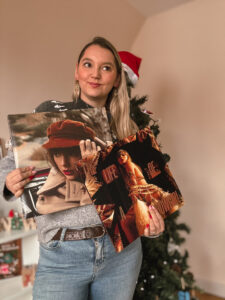 Sorbet-Kiwi tient deux vinyles aux couvertures de Red et TLOAS. Le sapin décoré est visible à côté. La personne porte un pull gris et un jean.