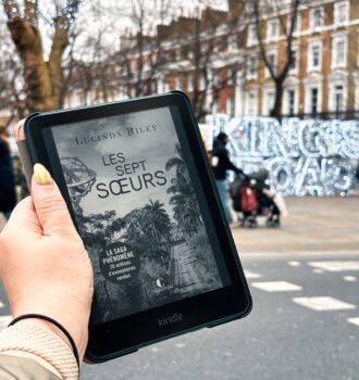 Kindle affichant Les Sept Sœurs de Lucinda Riley dans une rue londonienne hivernale décorée de lumières, King's Road en lumière en fond.