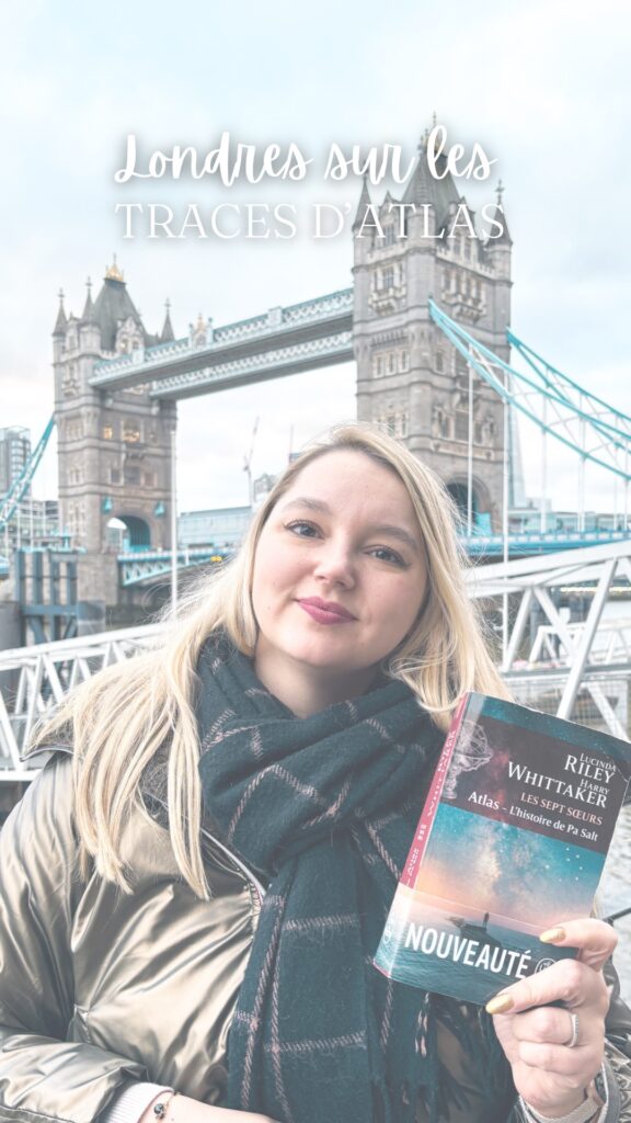 Stéphanie tenant le roman Atlas, l’histoire de Pa Salt devant Tower Bridge à Londres dans le cadre des traces d’Atlas.