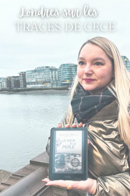 Stéphanie tenant une liseuse Kindle affichant La sœur à la perle de Lucinda Riley, au bord de la Tamise à Battersea à Londres, dans le cadre des traces de CeCe.
