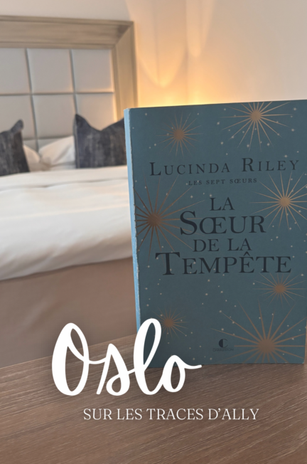 Le livre La Sœur de la tempête de Lucinda Riley posé sur une table en bois, avec en arrière-plan un lit et une tête de lit capitonnée du Grand Hotel d'Oslo. Le texte « Oslo Sur les traces d’Ally » est superposé en blanc.