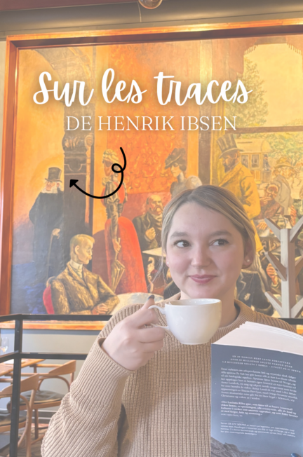 Sorbet-Kiwi sourit en tenant une tasse de café et le livre Stormens søster de Lucinda Riley, devant la fresque représentant Henrik Ibsen au Grand Café. Le texte « Sur les traces de Henrik Ibsen » est superposé en blanc.