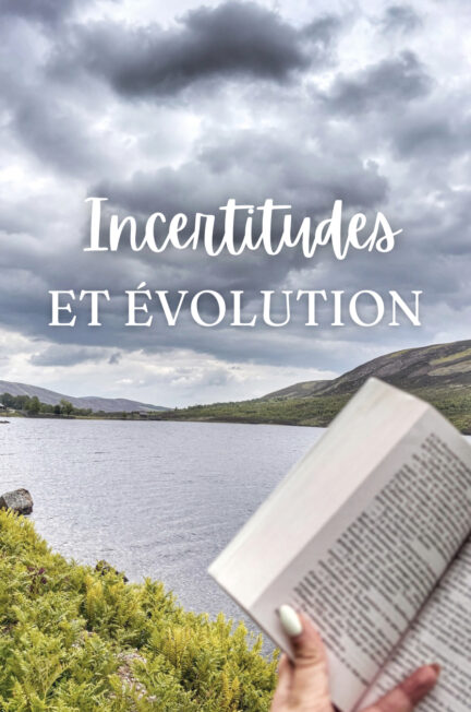 Livre ouvert tenu à lamain au bord d'un lac en Écosse sous un ciel nuageux avec collines en arrière-plan et texte "Incertitudes et évolution" affiché sur l'image en overlay blanc
