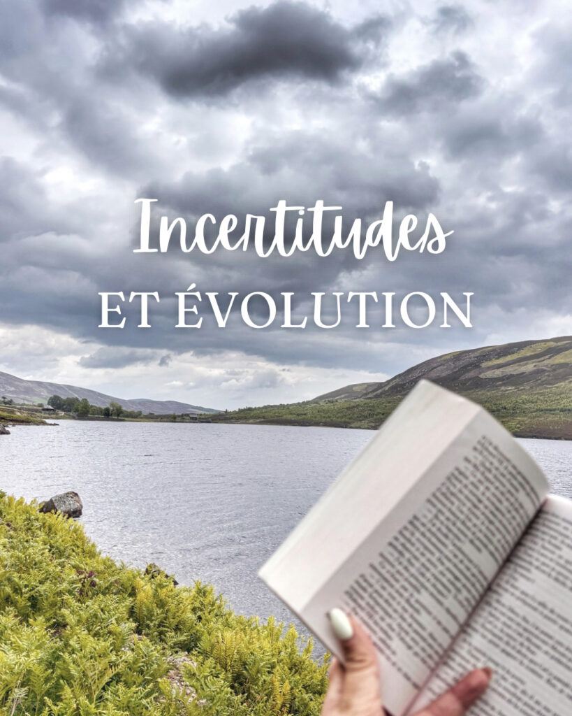 Livre ouvert tenu à lamain au bord d'un lac en Écosse sous un ciel nuageux avec collines en arrière-plan et texte "Incertitudes et évolution" affiché sur l'image en overlay blanc