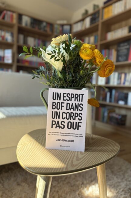 livre Un esprit bof dans un corps pas ouf posé sur une table avec bouquet de fleurs dans un salon avec une bibliothèque en arrière plan