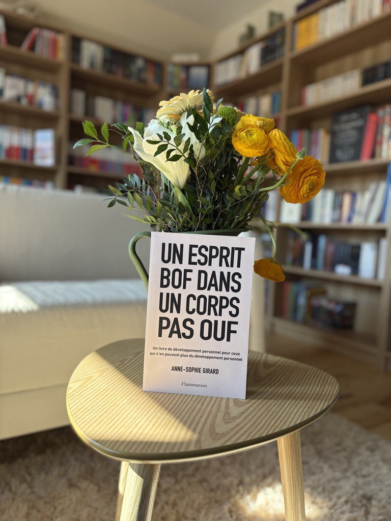 livre Un esprit bof dans un corps pas ouf posé sur une table avec bouquet de fleurs dans un salon avec une bibliothèque en arrière plan