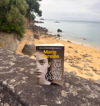 Le roman Nous qui avons connu Solange de Marie Vareille posé sur un muret face à la plage de Tréboul à Douarnenez, en Bretagne.