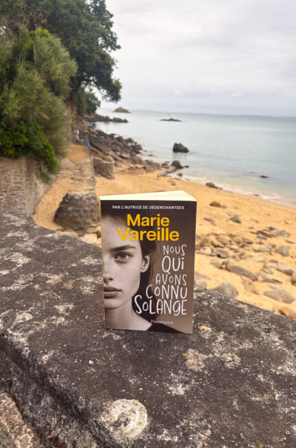 Le roman Nous qui avons connu Solange de Marie Vareille posé sur un muret face à la plage de Tréboul à Douarnenez, en Bretagne.