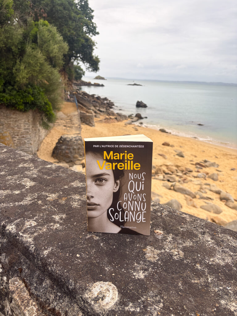 Le roman Nous qui avons connu Solange de Marie Vareille posé sur un muret face à la plage de Tréboul à Douarnenez, en Bretagne.