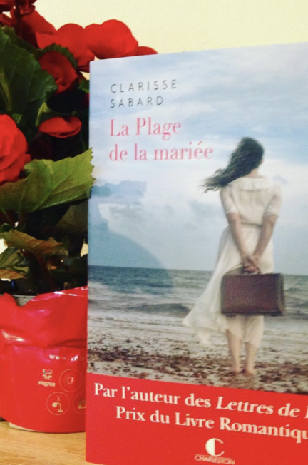 Le livre la plage de la mariée à côté d'un bouquet de fleurs rouges
