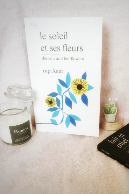 Le soleil et ses fleurs sur un fond rose accompagné d'une bougie et du recueil de nouvelles Lait et miel