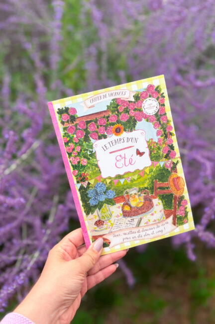 Le cahier de vacances Le temps d'un été de Caro From Woodland photographié devant un massif de fleurs violettes de mon jardin.
