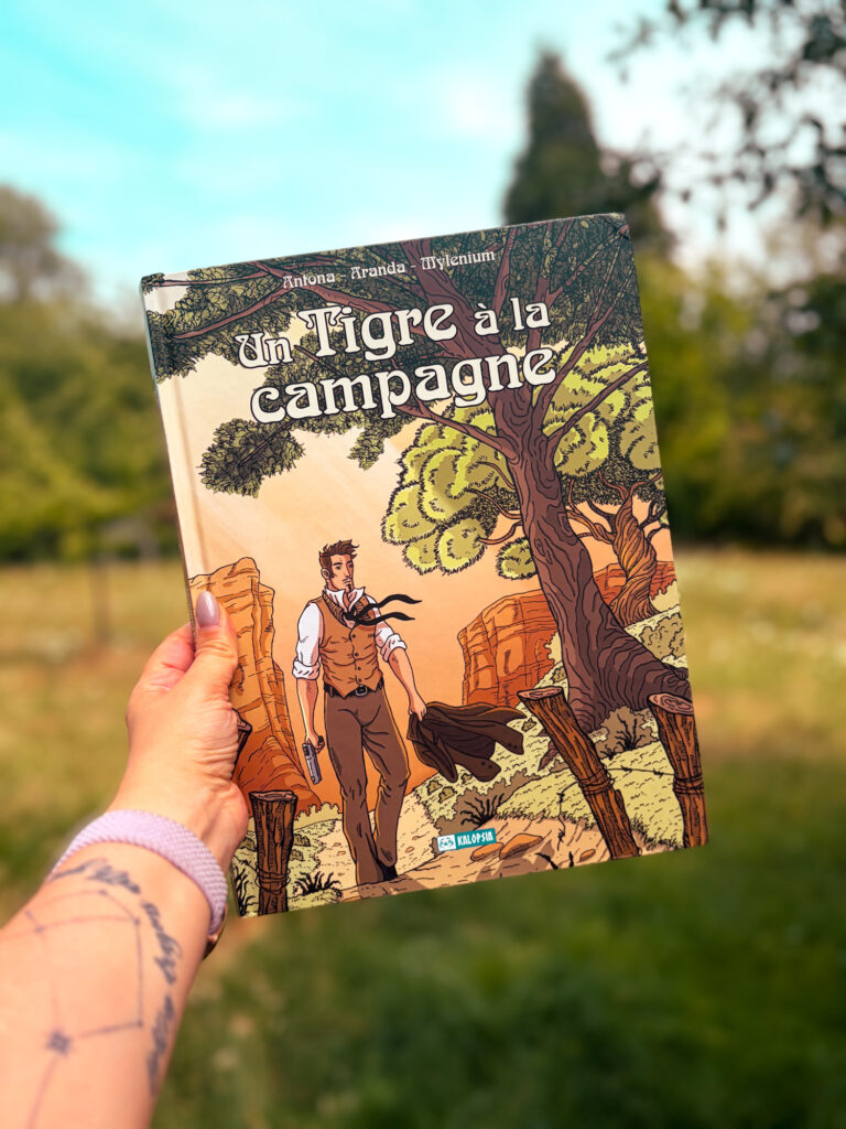 La bande dessinée Un tigre à la campagne de Nicolas Antona, Olivier Aranda et Mylenium photographiée dans un jardin, devant un paysage verdoyant.