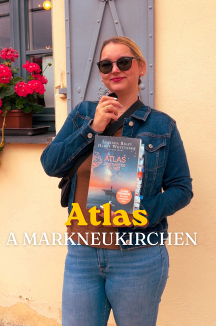 Une femme tenant le roman Atlas, l’histoire de Pa Salt de Lucinda Riley et Harry Whittaker devant le musée des instruments de musique de Markneukirchen, en Allemagne.