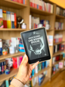 Une bonne épouse de Ingrid Desjours sur une liseuse avec une bibliothèque en arrière-plan