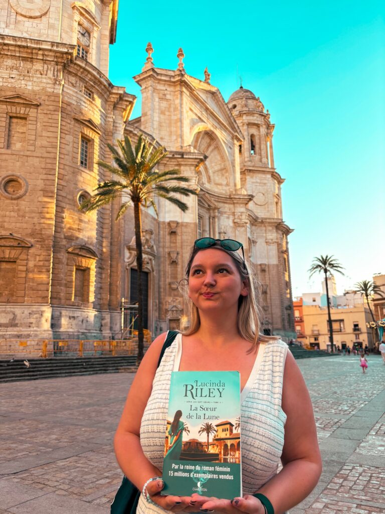 Sorbet-Kiwi tient le tome 5 des sept soeurs devant la cathédrale de Cadix