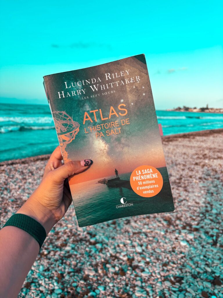 Une main tient Atlas l'histoire de Pa Salt sur une plage de Dénia